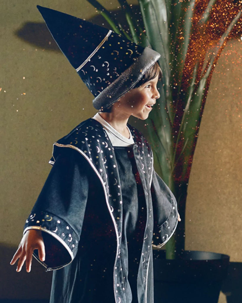 Petit garçon portant une tunique de magicien et un chapeau de magicien noir avec des petites étoiles et des petites lunes argentées